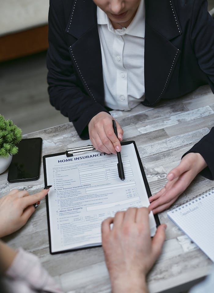 pexels-photo-7731328 An agent and clients discussing paperwork for home insurance at a meeting table.